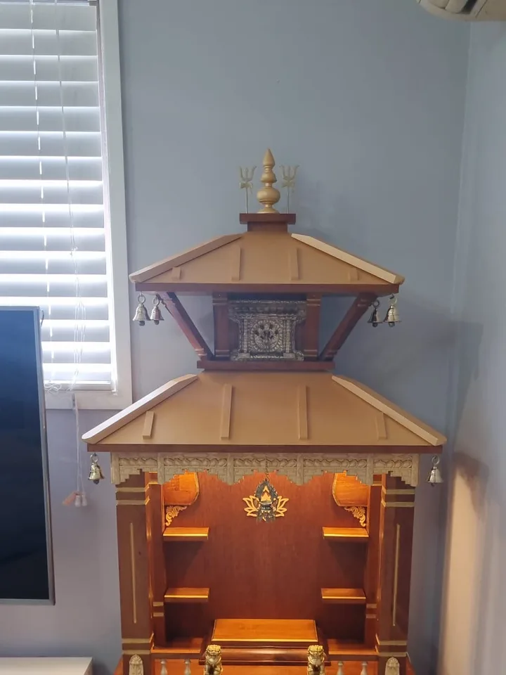 Brown Japan two-tier mandir with a carved Newari window and hanging brass bells
