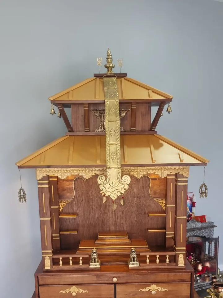 Two-tier teak pagoda mandir with pale gold roofs and an engraved brass patakha banner