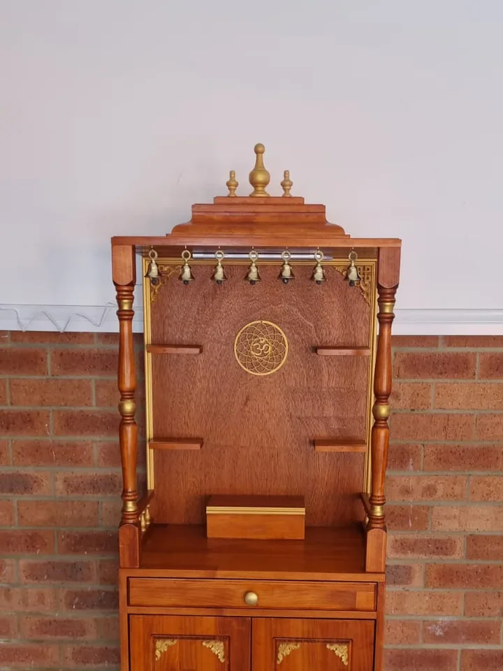 Slim teak mandir sized for a narrow wall, with a gold om roundel and cupboard base