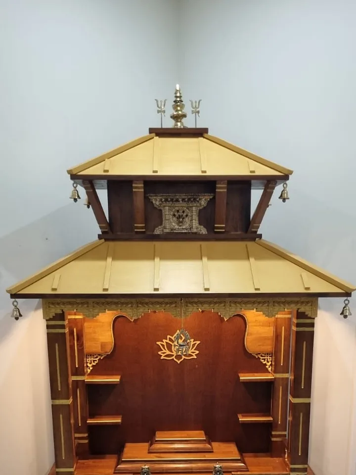 Two-tier teak pagoda mandir on a marble floor, with a carved torana and brass finial
